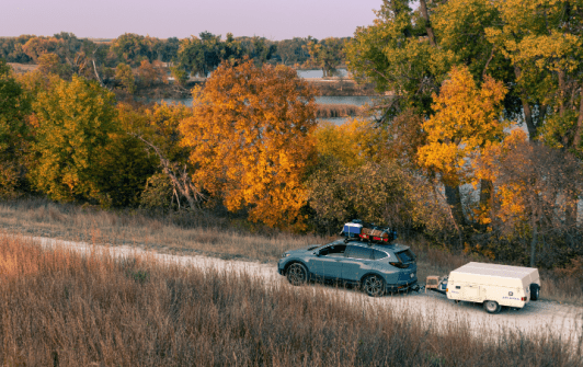 SUV Towing a Camping Trailer Down a Dirt Road